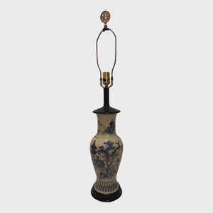 May include: A decorative table lamp with a ceramic base featuring a blue and white landscape design. The lamp has a black base and top, a brass-colored neck, and a decorative finial. The lamp is approximately 28 inches tall.