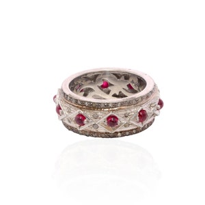 May include: A silver ring with a band of alternating diamonds and red gemstones. The ring is set in a delicate, intricate design.