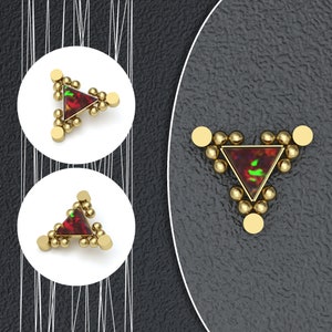 May include: A gold triangle with a red and green iridescent gemstone in the center. The triangle is surrounded by small gold beads.