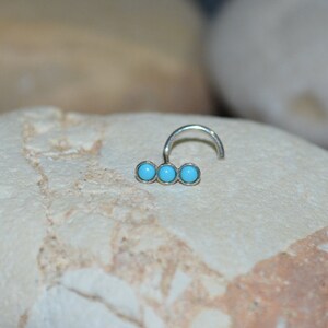 May include: A silver nose ring with three turquoise stones.