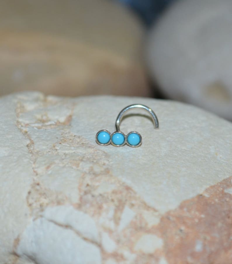 May include: A silver nose ring with three turquoise stones.