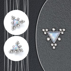 May include: A silver triangle body jewelry with a white opal-like stone in the center. The triangle is surrounded by small silver balls.
