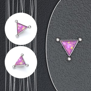 May include: A silver triangle body jewelry with a pink opal gemstone. The jewelry has three small silver balls on each corner of the triangle.