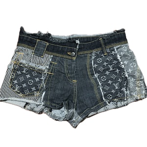 May include: Patchwork denim shorts in various shades of blue and grey. The shorts incorporate sections of striped fabric and a logo pattern. Yellow stitching and a button fastening are visible. The shorts have a frayed hem.