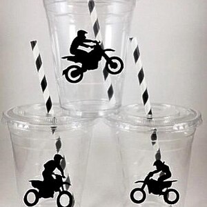 K&ouml;nnte beinhalten: Drei durchsichtige Plastikbecher mit schwarz-wei&szlig; gestreiften Strohhalmen. Jeder Becher hat eine schwarze Silhouette eines Motocross-Fahrers auf einem Dirtbike.