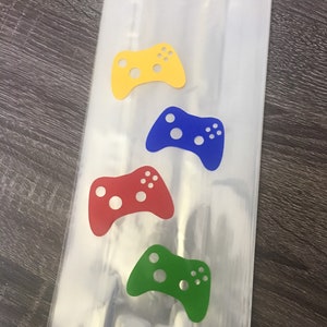 May include: Four clear plastic bags with colorful game controller cutouts. The controllers are yellow, blue, red, and green.