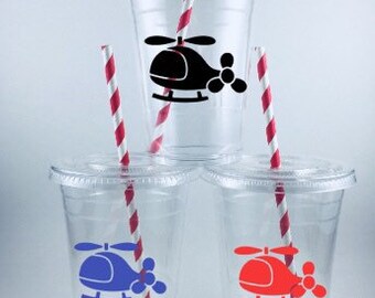 May include: Three clear plastic cups with red and white striped straws. Each cup has a helicopter design with different colors: black, blue, and red.