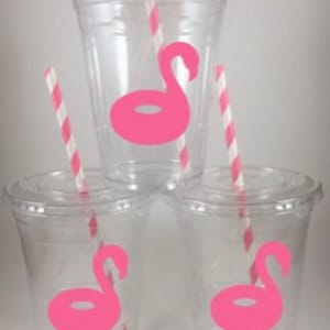 May include: Three clear plastic cups with pink flamingo pool float decals and red and white striped straws.