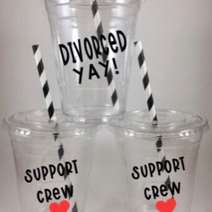 May include: Three clear plastic cups with black and white striped straws. The center cup has the text "Divorced Yay!" printed on it. The two cups on either side have the text "Support Crew" printed on them with a red heart.