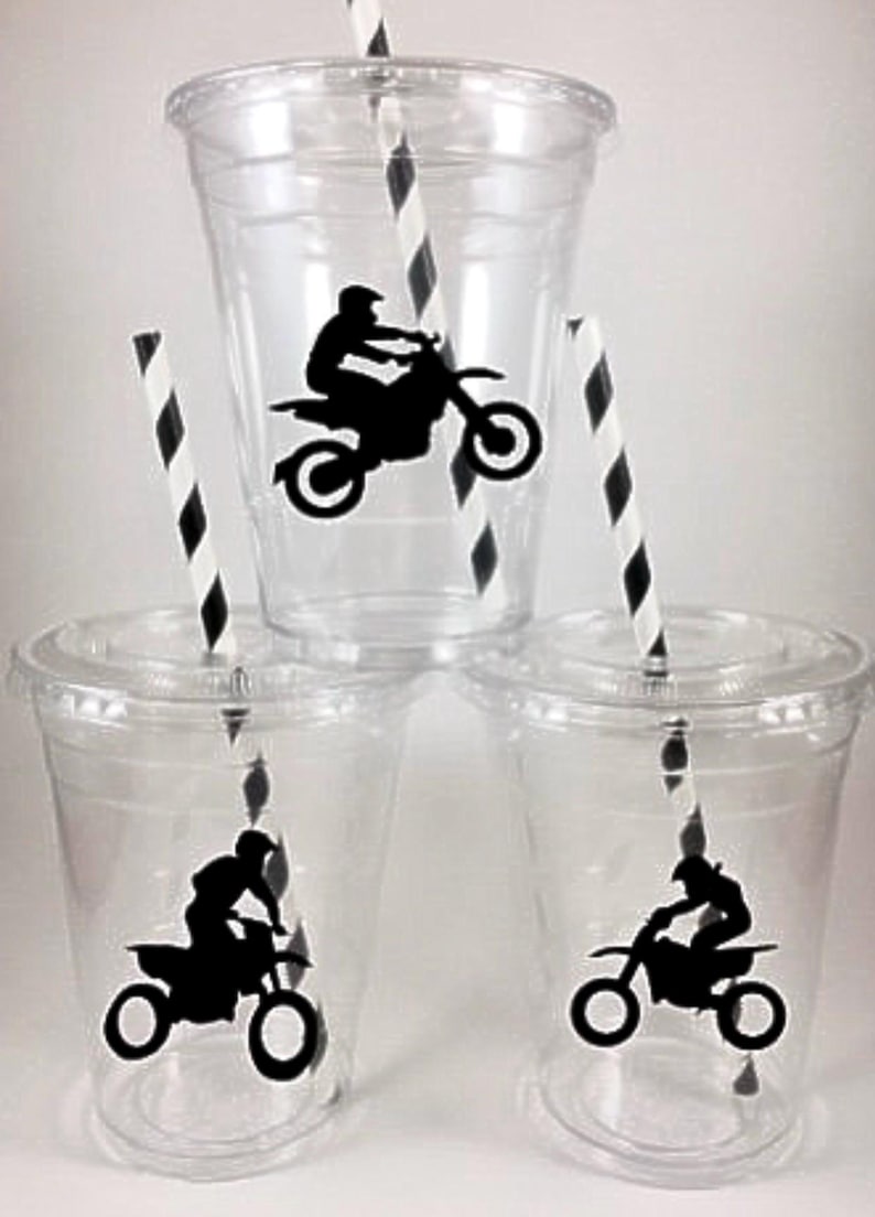 K&ouml;nnte beinhalten: Drei durchsichtige Plastikbecher mit Deckeln und schwarz-wei&szlig; gestreiften Strohhalmen. Jeder Becher hat eine schwarze Silhouette einer Person, die ein Dirtbike f&auml;hrt.