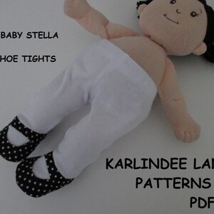 May include: White doll tights with black polka dot shoes. The doll is laying on a white surface. The text "FITS BABY STELLA SHOE TIGHTS KARLINDEE LANE PATTERNS PDF" is visible in the image.