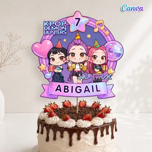 May include: A birthday cake with a decorative topper featuring three cartoon characters, the text "KPOP DEMON HUNTERS", and the name "ABIGAIL". The cake is decorated with chocolate frosting, whipped cream, and strawberries.