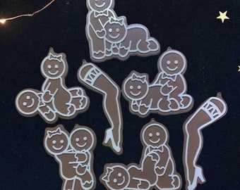 May include: A set of eight gingerbread person ornaments, each with a different pose. The ornaments are white on a dark background.
