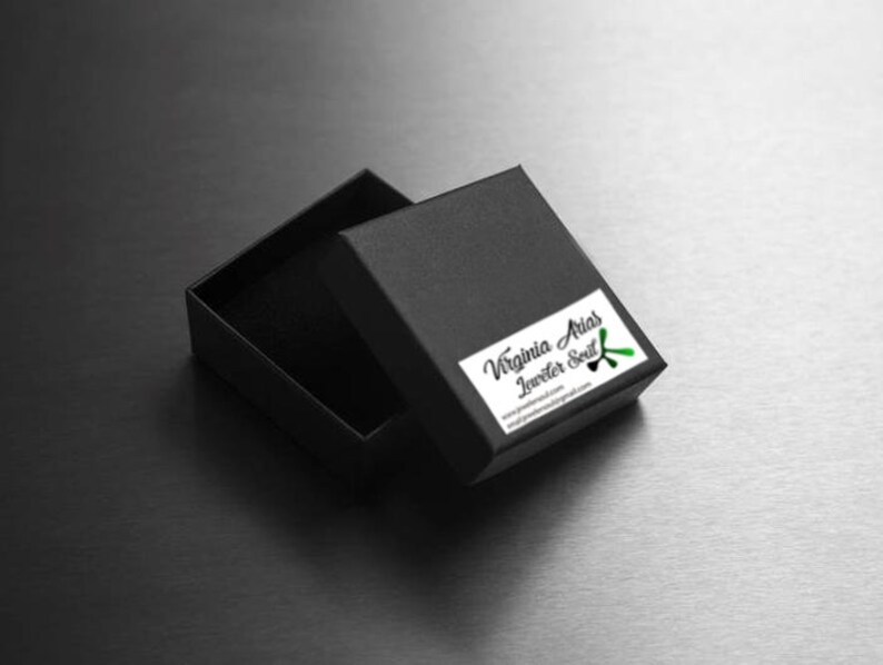 May include: A black jewelry box with a green and black logo that says "Virginia Arias Jeweler Soul" and the website address "virginiaariasjewelry.com".