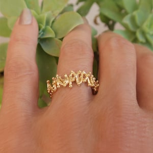 May include: A gold ring with a delicate, intricate design. The ring is made of small, interconnected loops and circles, creating a unique and modern look.