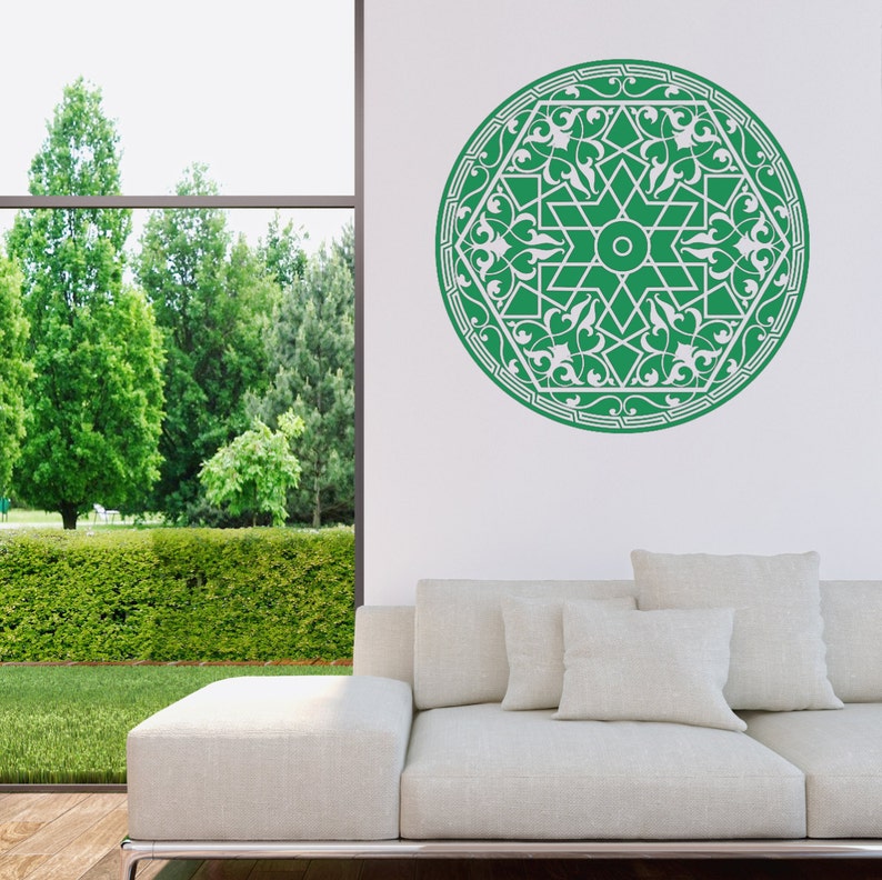 May include: A green and white mandala wall decal with intricate floral designs. The decal is applied to a white wall in a living room setting.