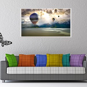 May include: A living room interior with a gray couch, colorful throw pillows, and wall decor. The wall decor includes a framed print of hot air balloons over a lake, a bamboo plant with butterflies, and a silhouette of a woman with a water jug, with the word "AFRICA" written above her.
