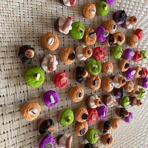 May include: A collection of miniature Halloween cupcakes with various colorful frostings and spooky decorations. The cupcakes are arranged on a woven surface.