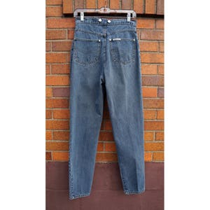 May include: A pair of high-waisted, light blue denim jeans with a button fly and belt loops. The jeans have a straight leg fit and are hanging on a hanger.