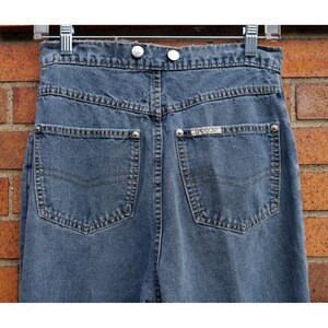 May include: A pair of blue denim jeans with a back pocket that has the word "Guess" embroidered on it.