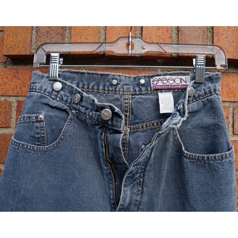 May include: A pair of blue denim jeans with a button fly and a