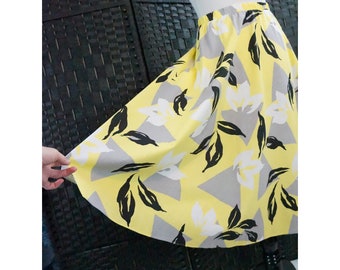 May include: A yellow, gray, and black floral skirt with a flared silhouette. The skirt has a simple elastic waistband.