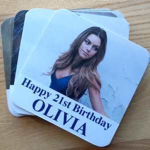 May include: A white card with a photo of a woman with long brown hair. The card says "Happy 21st Birthday Olivia" in blue text.