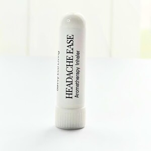 K&ouml;nnte beinhalten: Ein wei&szlig;er Aromatherapie-Inhalator mit dem Text "HEADACHE EASE" und "Aromatherapy Inhaler" in Schwarz aufgedruckt. Das Produkt tr&auml;gt auch den Text "Savvy Eco Living" auf der Seite.