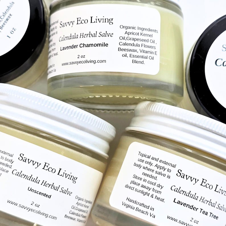 May include: Several glass jars of Savvy Eco Living Calendula Herbal Salve with white screw-top lids. The labels feature the product name, 2 oz weight, and organic ingredients including apricot kernel oil, grapeseed oil, and beeswax.