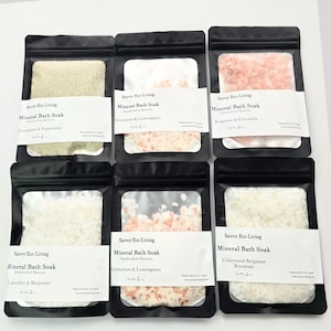 May include: Six black pouches of mineral bath soak with white labels. Scents include Eucalyptus & Peppermint, Geranium & Lemongrass, Bergamot & Citronella, Lavender & Marjoram, and Cedarwood Bergamot Rosemary.