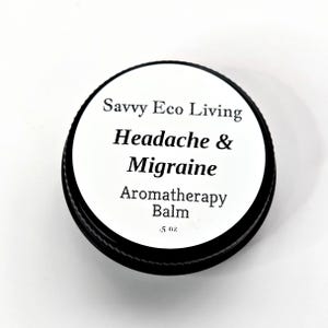 K&ouml;nnte beinhalten: Ein schwarzer, runder Beh&auml;lter mit wei&szlig;em Deckel. Der Deckel tr&auml;gt den Text "Savvy Eco Living Headache & Migraine Aromatherapy Balm" in Schwarz. Das Etikett gibt auch an, dass der Balsam 14 Gramm enth&auml;lt.