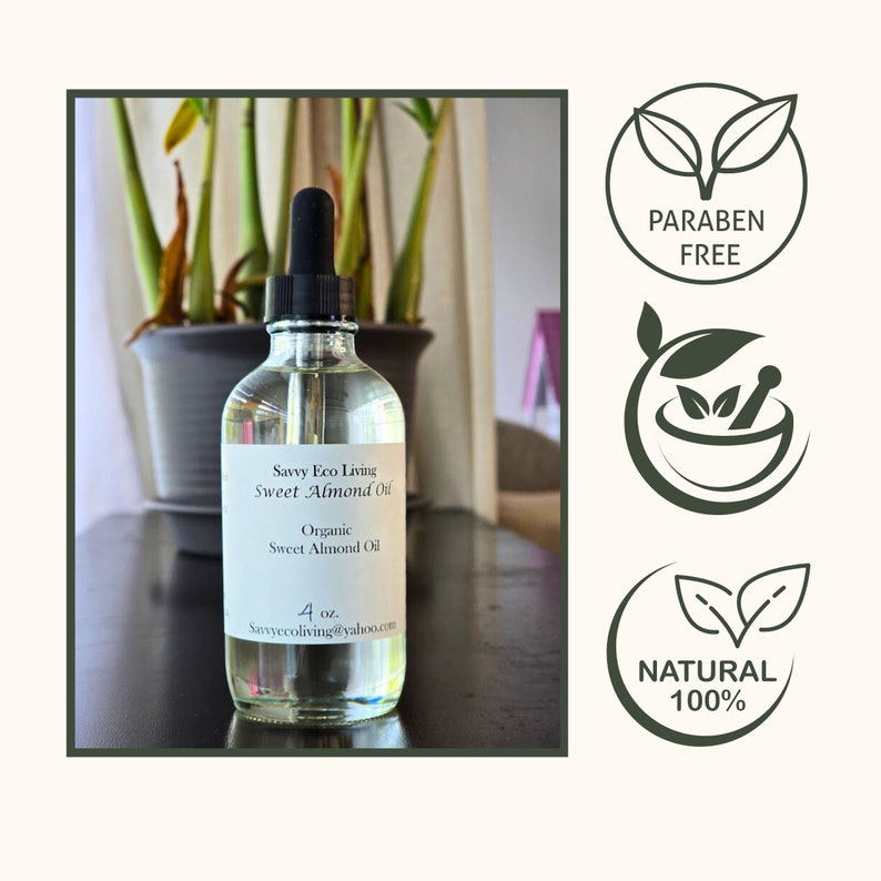 May include: A clear glass bottle with a dropper filled with organic sweet almond oil. The bottle has a white label with the text "Savvy Eco Living Sweet Almond Oil" and "Organic Sweet Almond Oil". The bottle is sitting on a wooden surface. The image also includes three green icons with the text "PARABEN FREE", "NATURAL 100%", and a mortar and pestle.