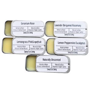 May include: A collection of lip balms in small, rectangular metal tins. Each tin is labeled with a different scent, including Geranium Rose, Lavender Bergamot Rosemary, and Lemon Peppermint Eucalyptus. The text "Savy Eco Living" is printed on each label.