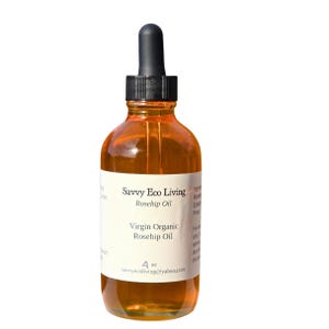 May include: A clear glass bottle of Savvy Eco Living Virgin Organic Rosehip Oil. The bottle has a black dropper and a white label with text. The oil is amber-colored and the bottle contains 4 oz of product.