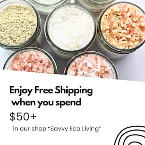 May include: Five glass jars filled with various bath salts and minerals. One jar contains a fine light green powder, another a white powder, and three jars contain coarse pink and white salt crystals. The jars have clear glass walls.