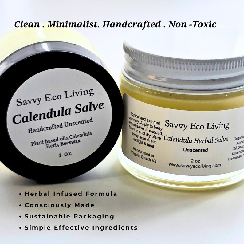 May include: Two round glass jars of Savvy Eco Living Calendula Salve with white labels and black text. The left jar has a black lid and is labeled 1 oz, while the right jar has a silver lid and is labeled 2 oz. The salve inside is a pale yellow color.
