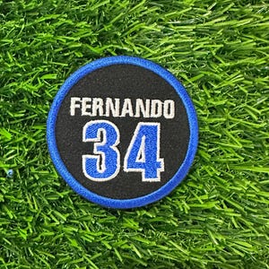 May include: A blue and black circular patch with the name "Fernando" and the number "34" in white.