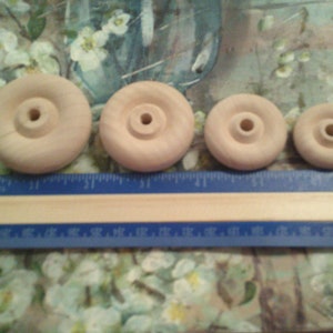 May include: Four unfinished wooden wheels of varying sizes. The wheels are arranged from largest to smallest. A ruler is placed below the wheels.