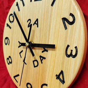 May include: A wooden clock with black numbers and hands. The clock face says "All Day" in black lettering.
