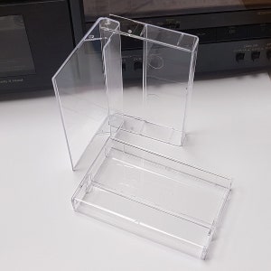 May include: Three clear plastic cassette tape cases. The cases are empty and are stacked on top of each other.