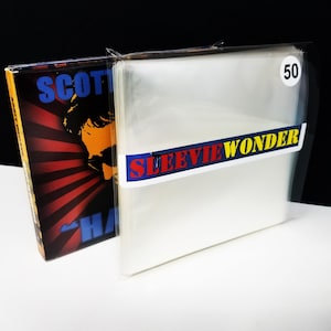 Peut inclure: Une pile de pochettes de protection en plastique transparent pour disques vinyles, étiquetée SLEEVIE WONDER avec un autocollant blanc indiquant le nombre 50. À côté se trouve une pochette de disque avec un motif rayonné rouge et noir.