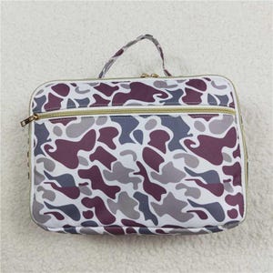 May include: A white, gray, and purple camouflage print zippered travel bag with a gold zipper.