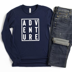 May include: A navy blue long-sleeved t-shirt with a white graphic that says "ADVENTURE" in a box.
