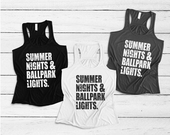 May include: Three tank tops with the text "SUMMER NIGHTS & BALLPARK LIGHTS." printed on them. The tank tops are black, white, and gray.