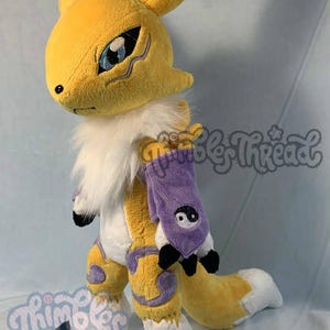 May include: A plush toy of a yellow fox-like creature with white accents, large ears, and a fluffy white collar. It has a purple arm sleeve with a yin-yang symbol and black claws. The toy is handmade.