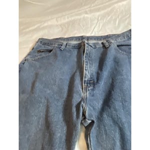 May include: Blue denim jeans with a classic five-pocket design. The jeans have a button and zipper closure, belt loops, and a relaxed fit. The denim has a medium wash with subtle fading.