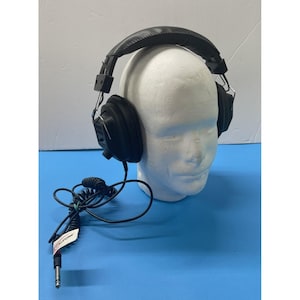 May include: Black over-ear headphones with a padded headband and earcups. The headphones have a coiled cord with a 1/4 inch (0.6 cm) audio jack. The headphones are resting on a white foam head.