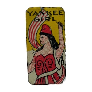 Puede incluir: Gráfico rectangular vintage con las palabras "YANKEE GIRL" sobre una ilustración de una mujer con vestido y sombrero rojos, sosteniendo una bandera. El fondo es amarillo con rayas rojas y blancas.