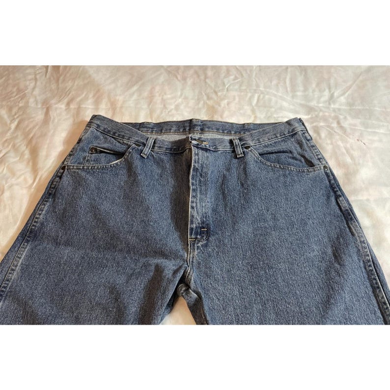 May include: A pair of blue denim jeans with a classic five-pocket design. The jeans have a button and zipper closure, belt loops, and a faded wash. The fabric appears to be sturdy and suitable for everyday wear.