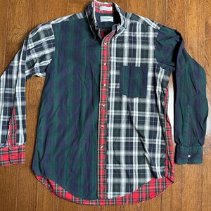 May include: A long-sleeved button-down shirt with a patchwork design. The shirt features a mix of plaid and striped patterns in green, navy, red, and white. The cuffs and hem are trimmed with red plaid. The shirt has a button-down collar and a chest pocket.